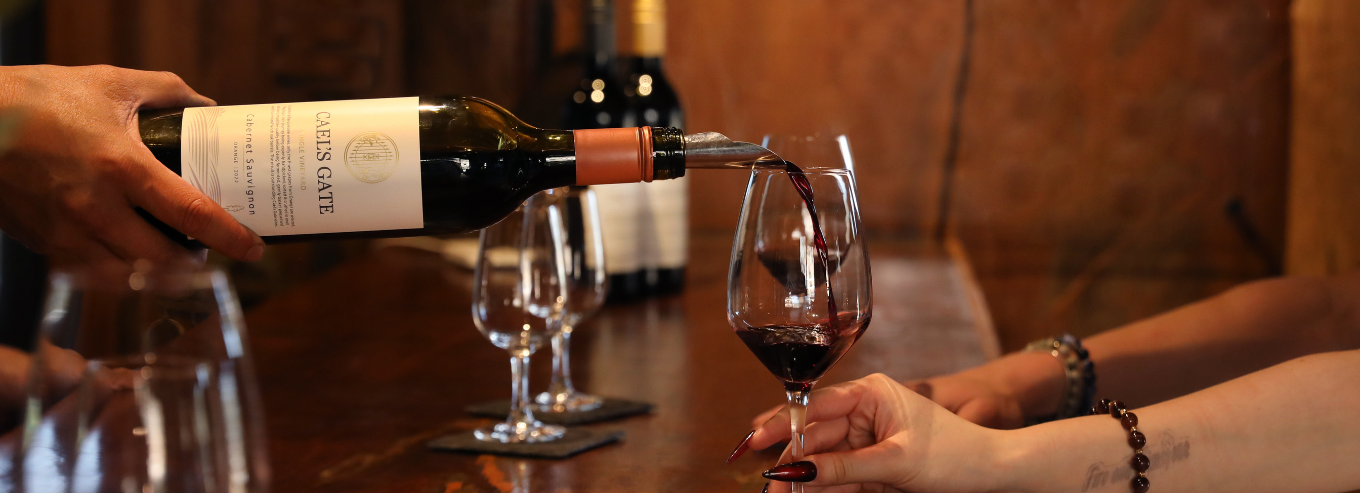 A bottle of Cael’s Gate Cabernet Sauvignon being poured into wine glasses 